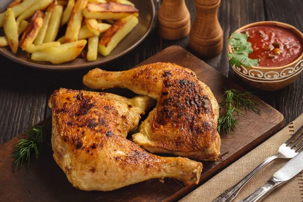 Roasted chicken legs with fried potatoes and tomato dip.